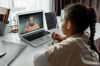 A girl sits with a laptop taking classes online.